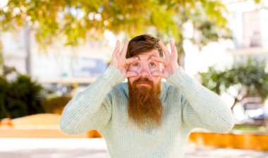 Kızıl sakallı adam sana göz kulak oluyor, güvenmiyor, izliyor, tetikte ve tetikte.