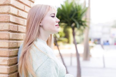 Profil görünümünde genç ve güzel bir kadın ilerideki boşluğu kopyalamaya çalışıyor, düşünüyor, hayal ediyor ya da hayal kuruyor.