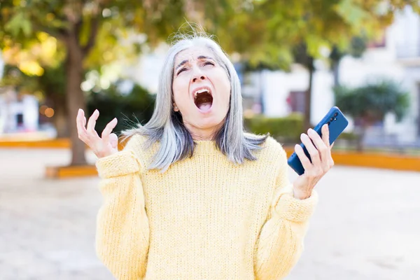Pretty Senior Woman Screaming Hands Air Smartphone — Stock Photo, Image