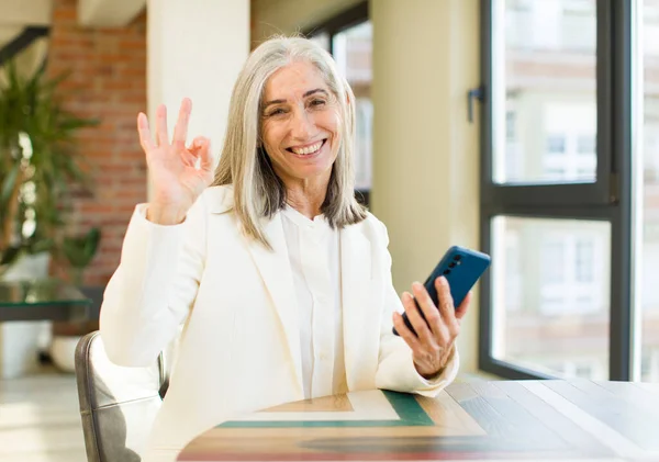 漂亮的老年女性感到快乐 用智能手机做一个好的手势表示赞同 — 图库照片