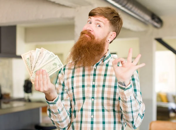 红头发的男人高兴极了 用美圆钞票做一个不错的手势表示赞同 — 图库照片