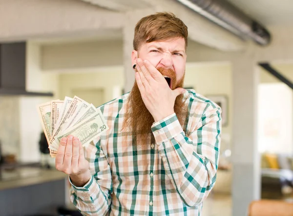 红头发的男人 嘴和眼睛睁得大大的 下巴上握着美元钞票 — 图库照片