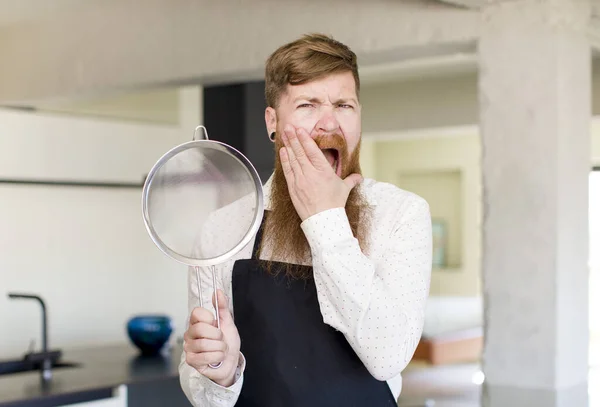 口と目の広い赤い髪の男がキッチンであごを開いて手をつないでいる シェフのコンセプト — ストック写真