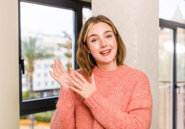 Kafkasyalı bir kadın mutlu ve başarılı hissediyor, gülümsüyor ve alkışlıyor, alkışlarla tebrik ediyor. ev içi konsept