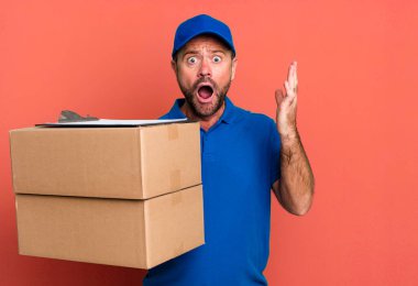 Orta yaşlı bir adam son derece şaşırmış ve şok olmuş hissediyor. Paker teslimatçısı. Paketçi teslimatçı