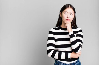 Güzel Asyalı kadın düşünüyor, kuşkulu ve şaşkın hissediyor.