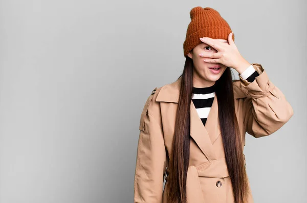 Stock image pretty asian woman looking shocked, scared or terrified, covering face with hand