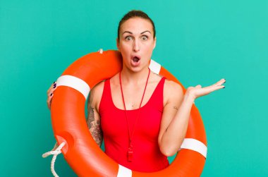 Genç ve güzel bir kadın şaşırmış ve şok olmuş görünüyor. Çenesi düşmüş ve elinde bir nesne tutuyor. yaz ve cankurtaran konsepti