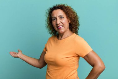 Orta yaşlı İspanyol kadın kendini mutlu ve neşeli hissediyor, gülümsüyor ve seni hoş karşılıyor, dostça bir jestle içeri davet ediyor.