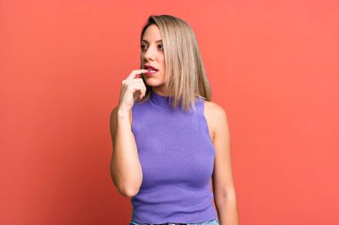 blonde adult woman with surprised, nervous, worried or frightened look, looking to the side towards copy space