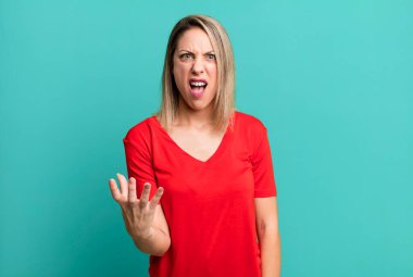 blonde adult woman looking angry, annoyed and frustrated screaming wtf or whats wrong with you 