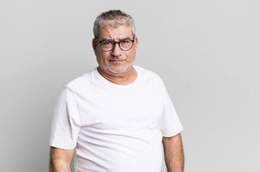 Orta yaşlı bir adam üzgün, üzgün ya da kızgın hisseder ve olumsuz bir tavır takınır, anlaşmazlıkla kaşlarını çatar.