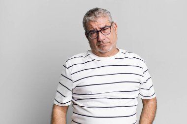 Orta yaşlı bir adam üzgün ve mızmız görünüyor. Mutsuz görünüyor. Olumsuz ve hayal kırıklığına uğramış bir tavırla ağlıyor.