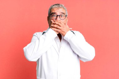 Orta yaşlı bir adam şok olmuş bir şekilde elleri ile ağzını kapatıyor. hekim ya da doktor konsepti