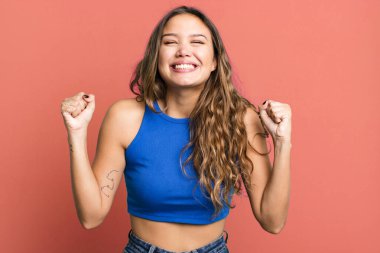 Genç ve güzel bir kadın son derece mutlu ve şaşırmış görünüyor, başarıyı kutluyor, bağırıyor ve zıplıyor.