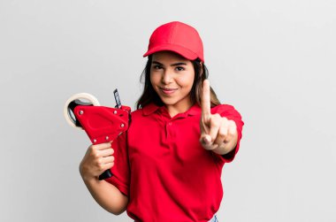 İspanyol güzel kadın gülümsüyor ve arkadaş canlısı görünüyor, bir numarayı gösteriyor. paketleyici ve dağıtım çalışanı