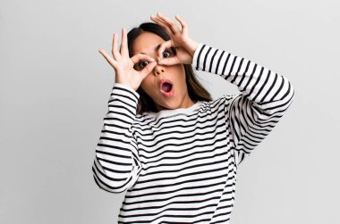 İspanyol güzel kadın şaşkın, şaşkın ve şaşırmış hissediyor, elinde şaşkın, inançsız bir bakışla gözlük tutuyor.