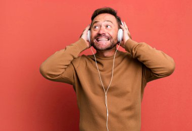 Orta yaşlı bir adam kulaklıklarıyla müzik dinliyor futbol topu ile spor koçluğu yapıyor.