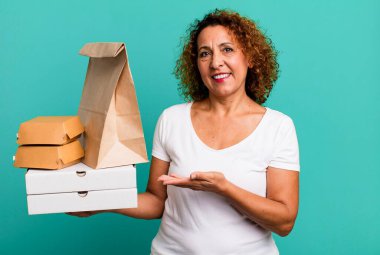 Neşeli bir şekilde gülümsemek, mutlu olmak ve bir konsept göstermek. Fast food dağıtım konseptini kaldır..