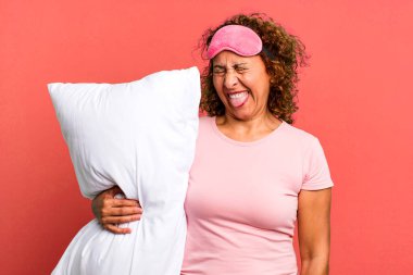 Güzel, orta yaşlı, neşeli ve asi tavırlı bir kadın, şaka yapıyor, pijamayla gece elbisesi giyiyor ve yastık takıyor.