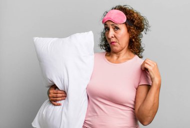 Güzel orta yaşlı bir kadın kibirli, başarılı, pozitif ve gururlu görünüyor pijama ve yastık giyiyor.