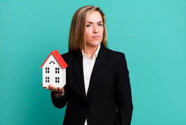 pretty blonde woman feeling sad, upset or angry and looking to the side. real state concept