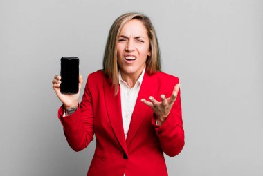 Güzel sarışın kadın sinirli, sinirli ve sinirli görünüyor. İş kadını ve telefon konsepti