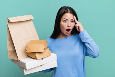 İspanyol güzel kadın şaşırmış görünüyor, yeni bir düşünce, fikir ya da konsept fark ediyor. Fast food paketleriyle birlikte.