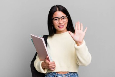 hispanic pretty woman smiling and looking friendly, showing number five. university student concept
