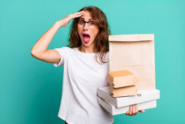 İspanyol güzel kadın mutlu, şaşkın ve şaşırmış görünüyor. Fast food paketleri kavramını kaldır