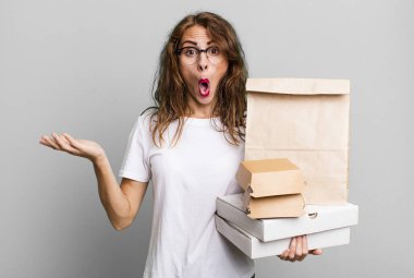 İspanyol güzel kadın şaşırmış ve şok olmuş görünüyor. Çenesi düşmüş ve elinde bir nesne var. Fast food paketleri kavramını kaldır