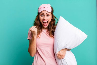 İspanyol güzel kadın şokta, gülüyor ve başarıyı pijama ve yastıkla kutluyor.