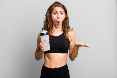 İspanyol güzel kadın şaşırmış ve şok olmuş görünüyor. Çenesi düşmüş ve elinde bir nesne var. fitness ve egzersiz konsepti