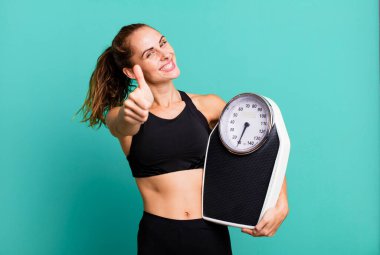 İspanyol güzel kadın gururlu, başparmağıyla olumlu gülümsüyor. fitness, diyet ve ağırlık ölçeği kavramı