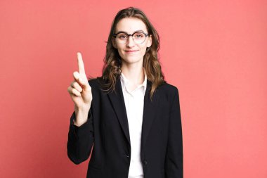 Genç, güzel bir bayan gülümsüyor ve arkadaş canlısı görünüyor. Bir numarayı gösteriyor. iş kavramı