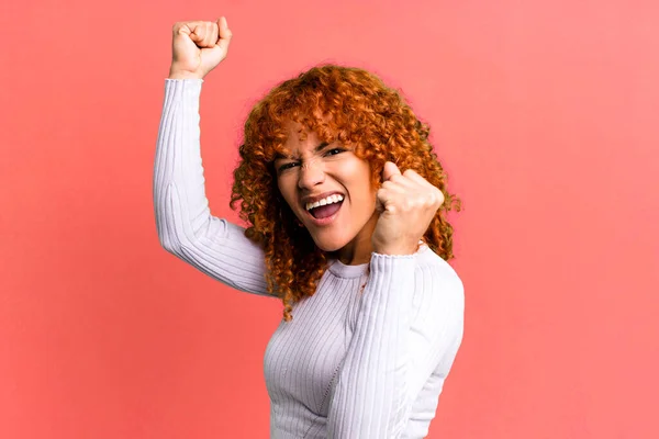 Stock image redhair pretty woman shouting triumphantly, looking like excited, happy and surprised winner, celebrating