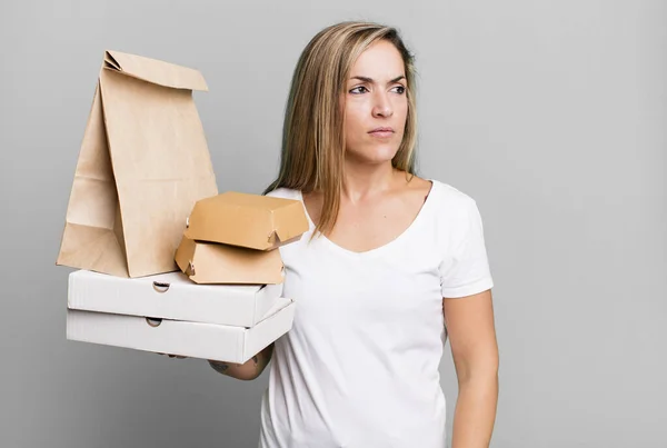 かなりブロンドの女性は悲しい 動揺している 怒っている 側を見ている 配送は食品パッケージの概念を取り除き — ストック写真