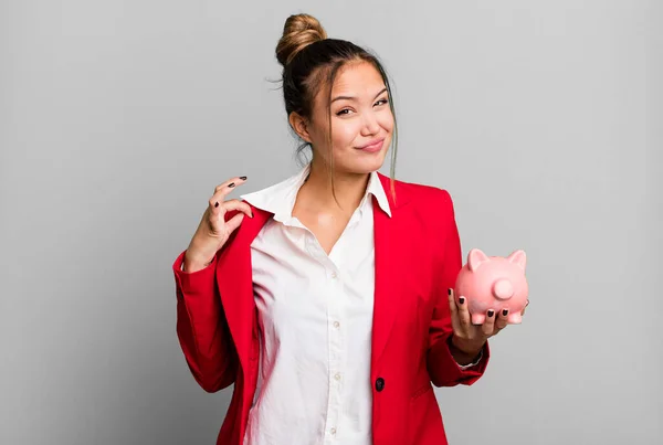hispanic pretty woman looking arrogant, successful, positive and proud with a piggy bank