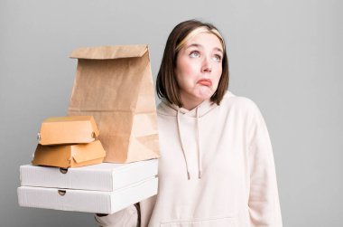 Genç, güzel bir kadın omuz silkiyor, kafası karışık ve kararsız. Fast food konseptini kaldır.