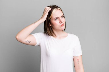 Kafası karışmış, kafası karışmış, kaşınan genç bir kadın.