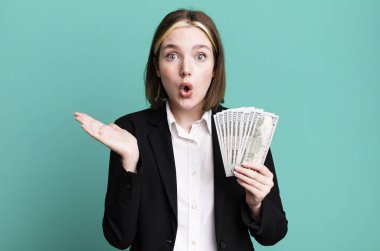 Genç ve güzel bir kadın şaşırmış ve şok olmuş görünüyor. Çenesi düşmüş ve elinde bir nesne tutuyor. Dolar banknotları