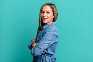 blonde adult woman smiling to camera with crossed arms and a happy, confident, satisfied expression, lateral view