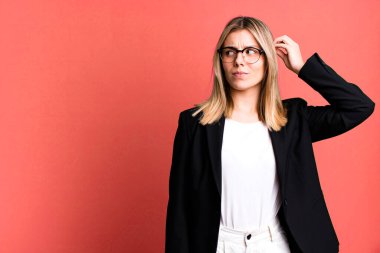 Genç, güzel bir kadın kafası karışmış, kafası karışmış, kaşınıyor. iş kavramı