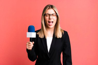 Genç ve güzel bir kadın agresif bir şekilde bağırıyor, çok kızgın görünüyor. sunucu veya gazeteci kavramı