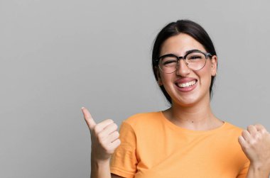 Neşeli bir şekilde gülümsüyor ve mutlu görünüyor, tasasız ve pozitif hissediyor.