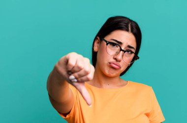 Kızgın, sinirli, hayal kırıklığına uğramış ya da hoşnutsuz, ciddi bir bakışla başparmaklarını aşağı gösteren.