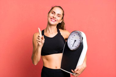 İspanyol güzel kadın gülümsüyor ve arkadaş canlısı görünüyor, bir numarayı gösteriyor. fitness, diyet ve ağırlık ölçeği kavramı