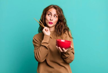 hispanic pretty young woman eating a japanese noodles bowl.