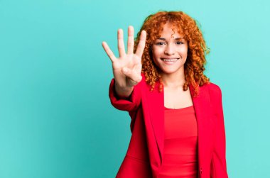 Kızıl saçlı güzel bayan gülümsüyor ve arkadaş canlısı görünüyor, dört numarayı gösteriyor. İş kadını kavramı