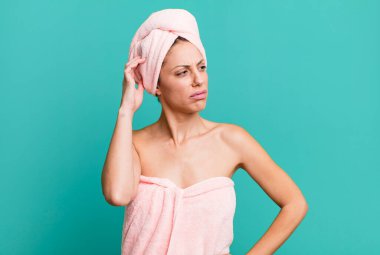 Güzel sarışın kadın mutlu bir şekilde gülümsüyor ve hayal kuruyor ya da şüphe ediyor. Bornoz ve güzellik konsepti